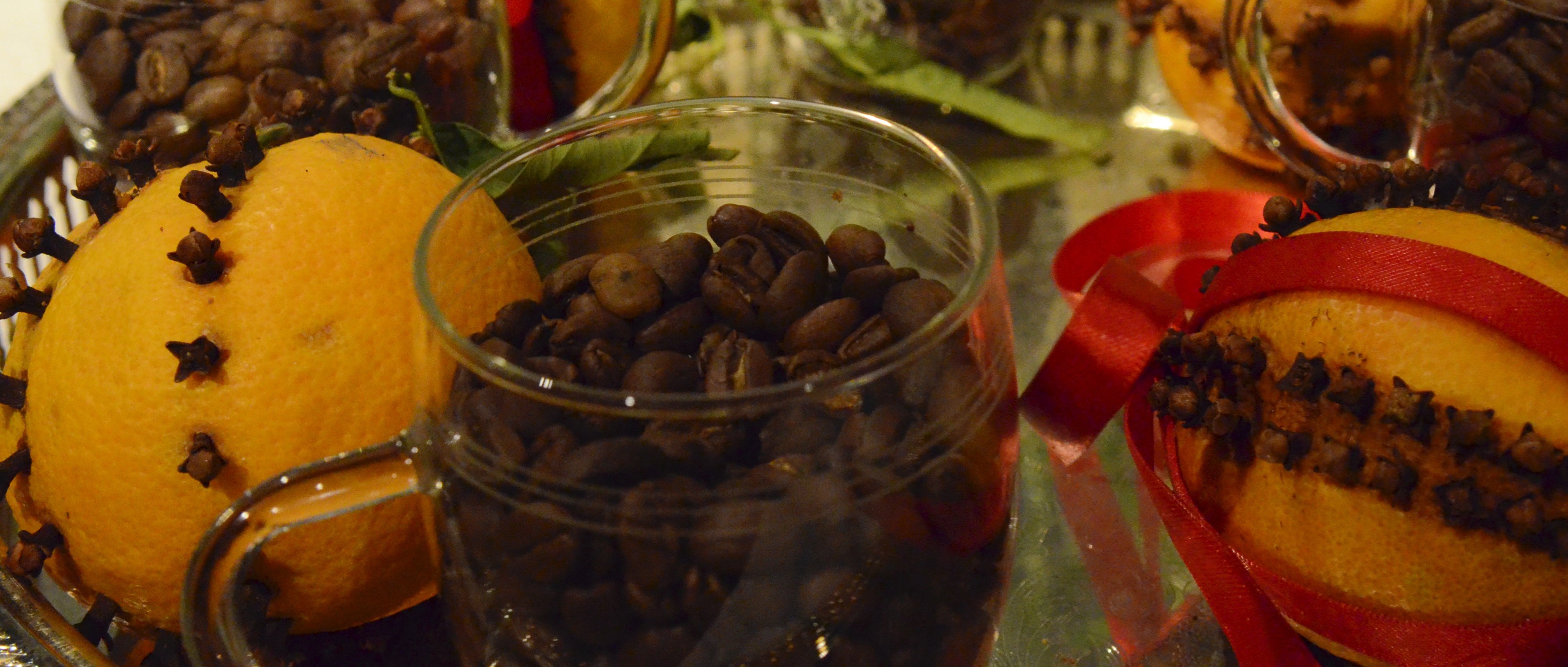 kaffebönor i glas på silverfat med juldekorerade nejlikapelsiner
